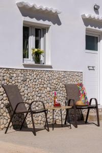 a patio with two chairs and a table and a building at Salty Beach Cottage, 20m from Kini Beach in Ano Syros