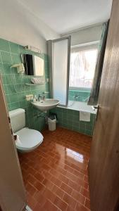een badkamer met een toilet, een wastafel en een bad bij Hotel Alpenrose in Zöblen