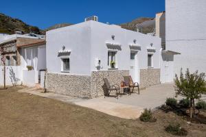 a white house with two chairs and a table at Salty Beach Cottage, 20m from Kini Beach in Ano Syros