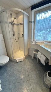 a bathroom with a shower and a toilet and a sink at Hotel Alpenrose in Zöblen
