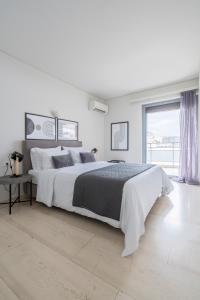 a white bedroom with a large bed and a window at SummerVibes Penthouse Varkiza in Vari