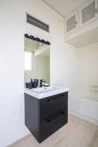 a bathroom with a sink and a mirror and a tub at SummerVibes Penthouse Varkiza in Vari