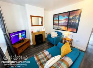 a living room with a blue couch and a tv at Blakefell by Prestige Properties SA in Arlecdon