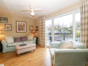 un salon avec deux canapés et un balcon dans l'établissement Mulberry Cabin On The Lake, à Caernarfon