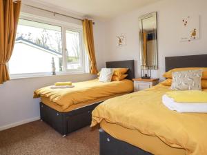 twee bedden in een kamer met een raam bij Blue Sky Cottage in Liskeard