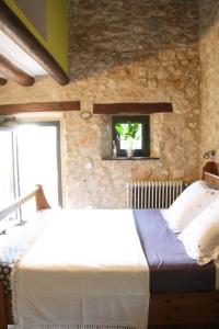 a bedroom with a large bed in a stone wall at Mas Coquells Rural - Habitació doble amb bany i terrassa privada in Vilanant