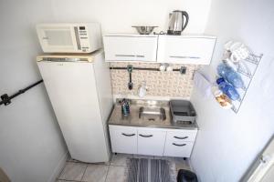 a small kitchen with a sink and a microwave at Apartamento central com pátio, 1 quadra do calçadão in Santa Maria