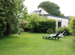 einen Garten mit zwei Stühlen und einem Tisch im Gras in der Unterkunft Les Clématites in Hillion