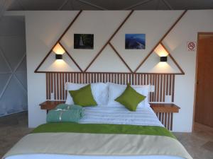 een slaapkamer met een groot bed met groene kussens bij Hotel Glamping & Restaurant Fuerza Ancestral in Tlalmanalco de Velázquez