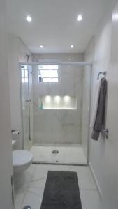 a white bathroom with a shower and a toilet at Duplex Impression Morumbi in São Paulo