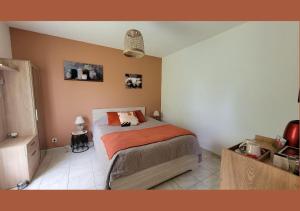 una camera con un letto e una coperta arancione di VIVRE BENAISE Chambre cosy & cuisine équipée a Chaunac