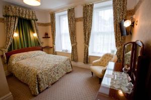 um quarto com uma cama, uma cadeira e janelas em Gwrach Ynys Country Guest House em Harlech