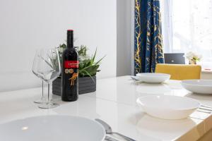Manor Terrace Retreat في أكرينغتون: زجاجة من النبيذ موضوعة على طاولة مع كوب
