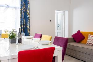 Manor Terrace Retreat في أكرينغتون: غرفة طعام مع طاولة بيضاء وكراسي ملونة