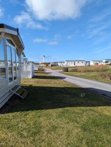 a house on the grass next to a sidewalk at D11 - the Dunes at Silver Sands in Lossiemouth