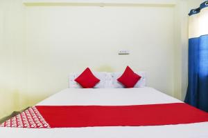 OYO Ruby Grand Inn في Kondapur: غرفة نوم بسرير ابيض ومخدات حمراء
