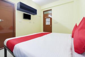 a bedroom with a white bed with red pillows at OYO Ruby Grand Inn in Kondapur