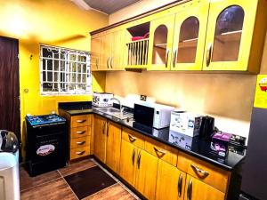 cocina con armarios de madera y encimera negra en Maryluxe Stays 6Bd villa, West hills, Accra Ghana, en Foso
