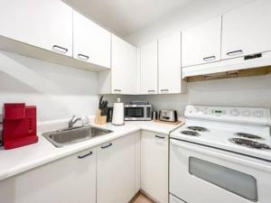 a white kitchen with a sink and a stove at Montreal Boutique Suites in Montréal