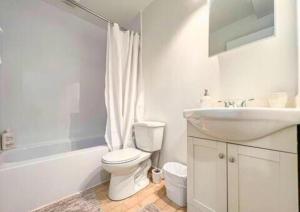 La salle de bains blanche est pourvue de toilettes et d'un lavabo. dans l'établissement Montreal Boutique Suites, à Montréal