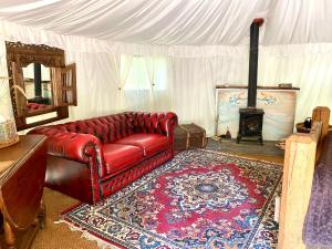 a living room with a red leather couch and a fireplace at Elessar Yurt Village in Chichester