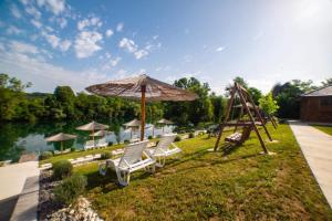 a playground with chairs and an umbrella and a swing at Una Relax in Bosanski Novi