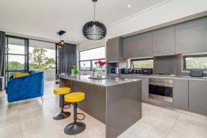 una cocina con armarios de acero inoxidable y taburetes amarillos en Luxurious & Peaceful Sandton 3-bed - Backup Power, en Johannesburgo