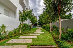 a walkway with grass and trees next to a building at Luxurious & Peaceful Sandton 3-bed - Backup Power in Johannesburg