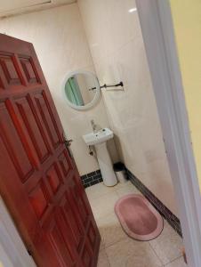 baño con aseo rosa y lavamanos en Bukari Executive Lodge, en Mpongwe