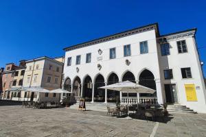 a large white building with tables and umbrellas at Altana Rooms Apartment in Koper