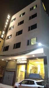 新德里的住宿－Prime Z Suites Hotel- Near Delhi International Airport，停在大楼前的白色汽车