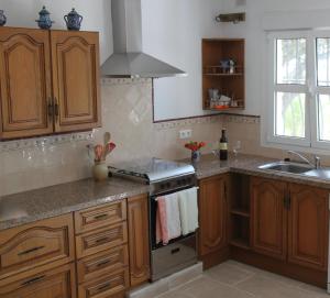 a kitchen with wooden cabinets and a stove top oven at Casa Christa in Alfarnate