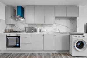 una cucina con armadietti bianchi e lavatrice di Stylish 3Bedroom House in Prime Leicester Location a Humberstone