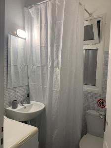 uma casa de banho com uma cortina de chuveiro branca e um lavatório. em Charming House in Central Athens em Atenas