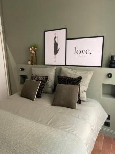 - un lit blanc avec des oreillers et 2 photos encadrées dans l'établissement La Halte des Arènes de Nîmes Emeraude, Havre de paix en ville, à Nîmes