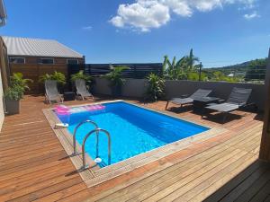 a swimming pool on a wooden deck next to a patio at Villa des Grenadelles in Saint-Paul