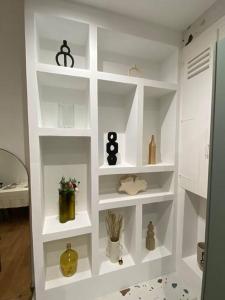 a white book shelf with vases and other items on it at La Halte des Arènes de Nîmes Emeraude, Havre de paix en ville in Nîmes