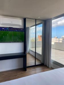 um quarto com uma televisão de ecrã plano e uma grande janela em Hotel Ciudadano Suites em Montevidéu