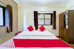 a bedroom with a large white bed with red pillows at Flagship Hotel Sai Residenci in Lonavala