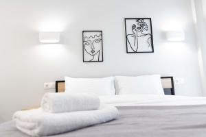 a white bed with two pictures on the wall at SKG Modernity Studio in Thessaloniki