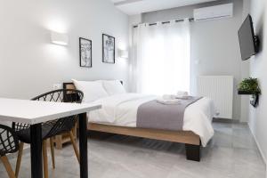 a white bedroom with a bed and a table at SKG Modernity Studio in Thessaloniki