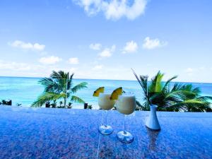 dos vasos en una mesa con el océano en el fondo en CARAIBICO STUDIOS Beach Club & Pool, en Punta Cana