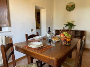 una mesa de madera con un bol de frutas y copas de vino en Agriturismo Podere le Tombe, en Palaia