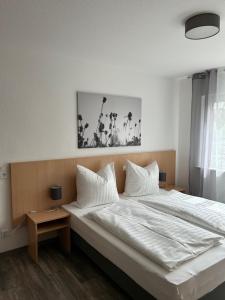 ein Schlafzimmer mit einem großen Bett mit weißer Bettwäsche und Kissen in der Unterkunft Pension im Wirtshaus Himberg in Bad Honnef am Rhein