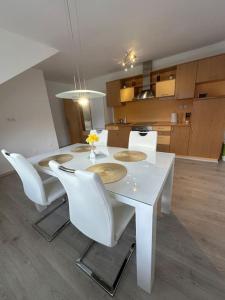 una mesa de comedor blanca con sillas blancas y una cocina en Prostorno in prijetno stanovanje en Smarjeske Toplice