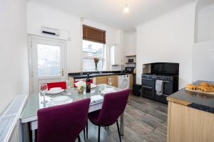 a kitchen with a dining table and purple chairs at Cosy Two bedroom Terrace Blackburn in Cherry Tree