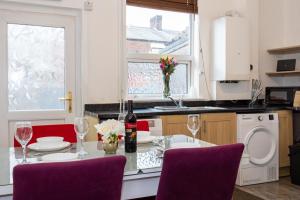 a kitchen with a table with wine bottles and chairs at Cosy Two bedroom Terrace Blackburn in Cherry Tree