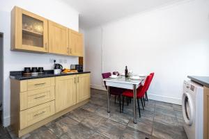 une cuisine avec des placards en bois et une table avec des chaises rouges dans l'établissement Cosy Two bedroom Terrace Blackburn, à Cherry Tree
