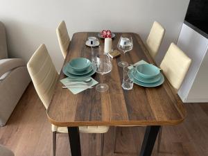 uma mesa de madeira com pratos e copos de vinho em Eliana Apartments em Druskininkai