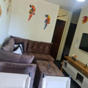 a living room with a couch and a tv at Apartamento Praia das Toninhas in Ubatuba